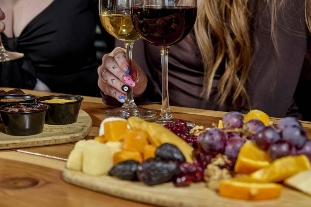 Woman's hand holding a glass of wine and enjoying snacks